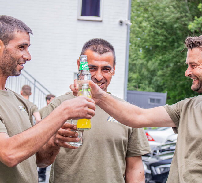 Drei Mitarbeiter trinken in der Pause gemeinsam etwas und lachen fröhlich.