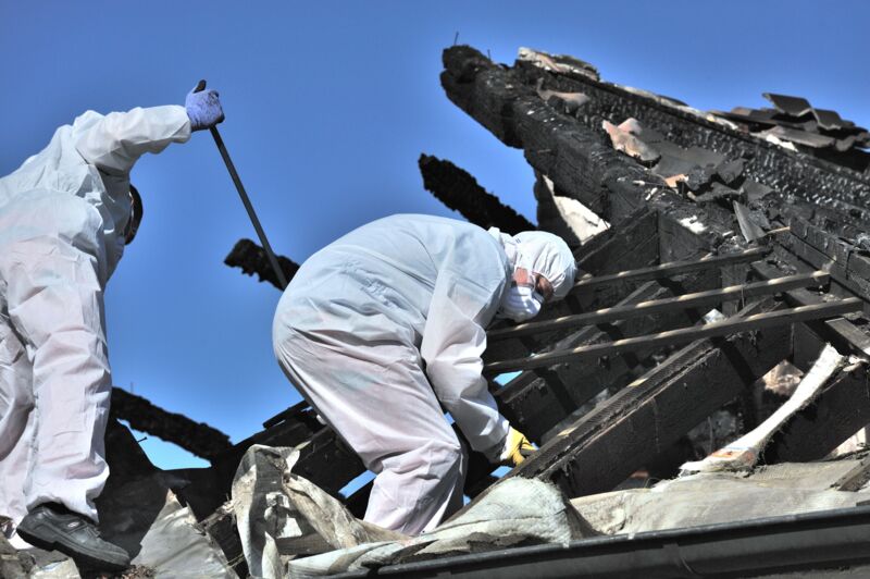 Zwei Mitarbeiter beseitigen einen Brandschaden und tragen dabei profssionelle Schutzausrüstung.