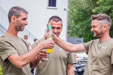 Drei Mitarbeiter trinken in der Pause gemeinsam etwas und lachen fröhlich.