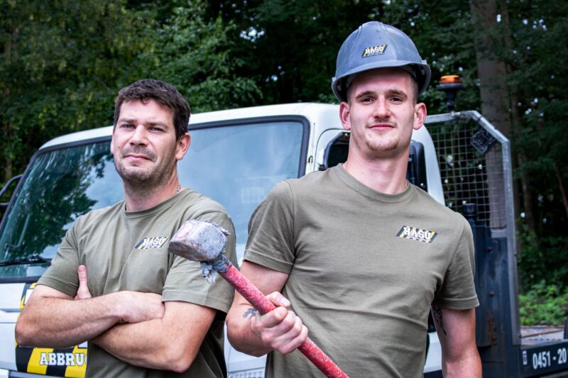 Zwei Mitarbeiter mit Hammer Porträt zweier Mitarbeiter bei HASU Abbruch. Ein Mitarbeiter hält einen Vorschlaghammer.