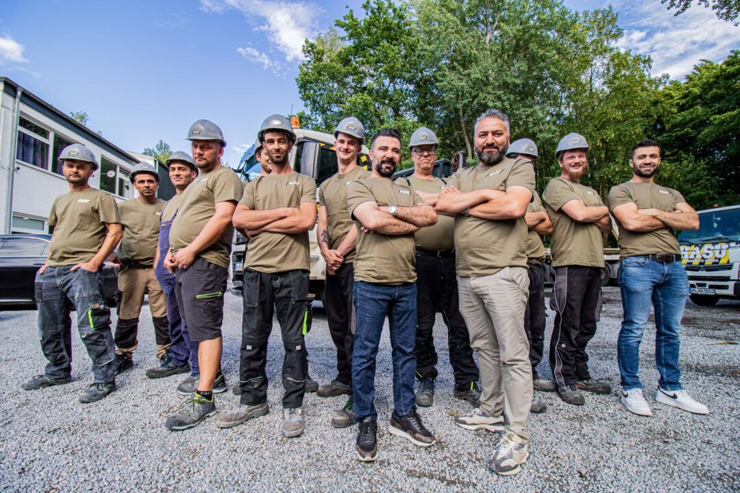 EIn Teamfoto aller Mitarbeiter der HASU Abbruch GmbH vor dem Hauptgebäude und einem LKW