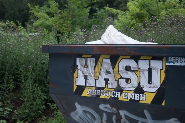 Ein HASu Container mit Logo, der gefüllt ist mit Müll von einem Abbruchprojekt.