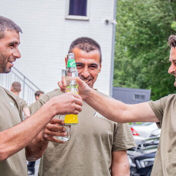 Drei Mitarbeiter trinken in der Pause gemeinsam etwas und lachen fröhlich.
