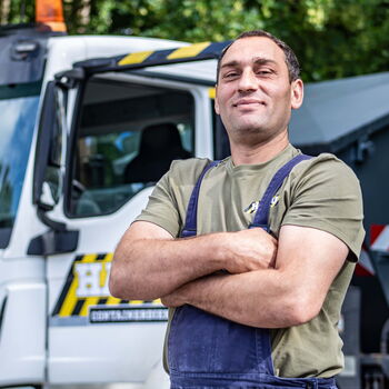 Porträt eines Mitarbeiters der HASU Abbruch GmbH vor einem LKW mit Containerladefläche